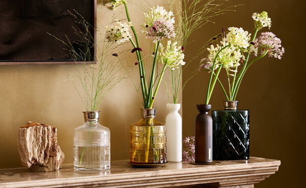 A collection of upcycled Rituals fragrance sticks bottles repurposed as elegant flower holders.